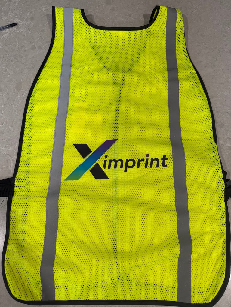 Bright yellow safety vest with reflective gray stripes and Ximprint logo on the front